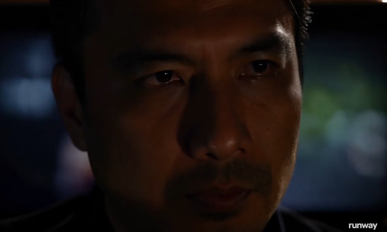 A cinematic wide portrait of a man with his face lit by the